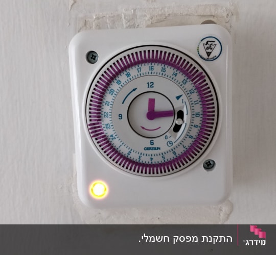 טיימר חשמלי עם מחוגים על קיר לבן